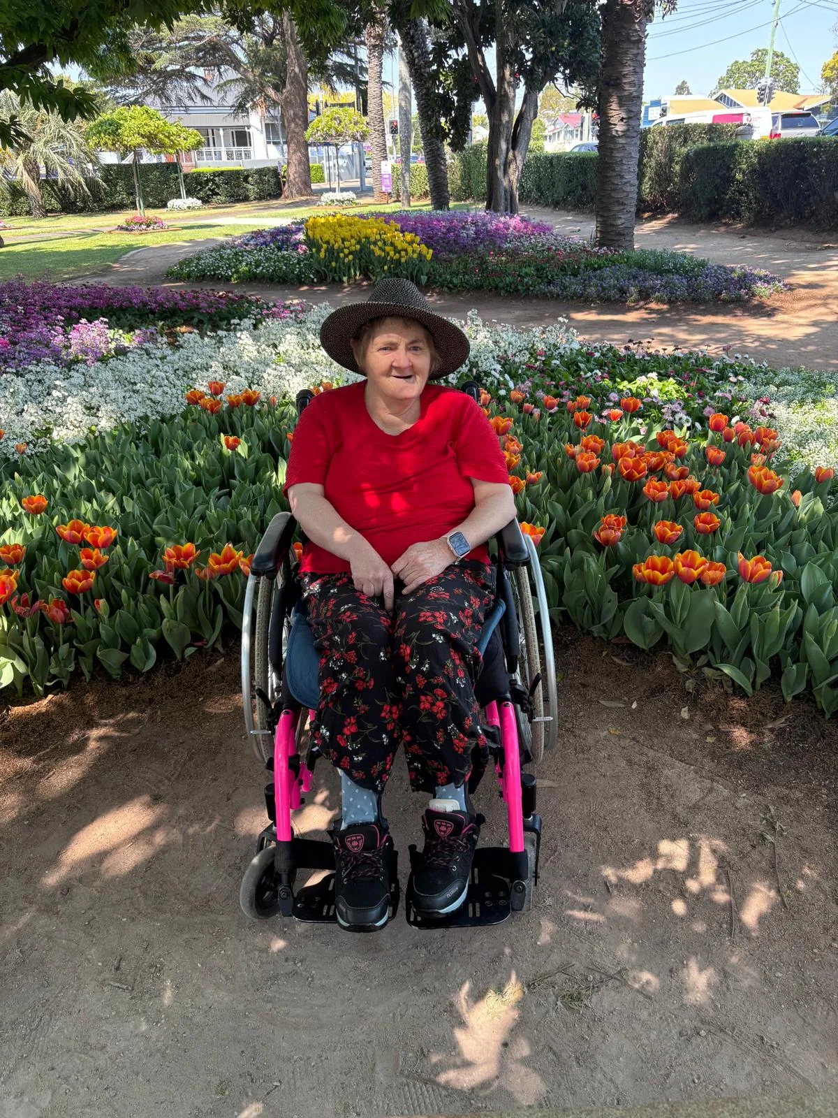 A participant in her wheelchair beside a tulip display in the gardens