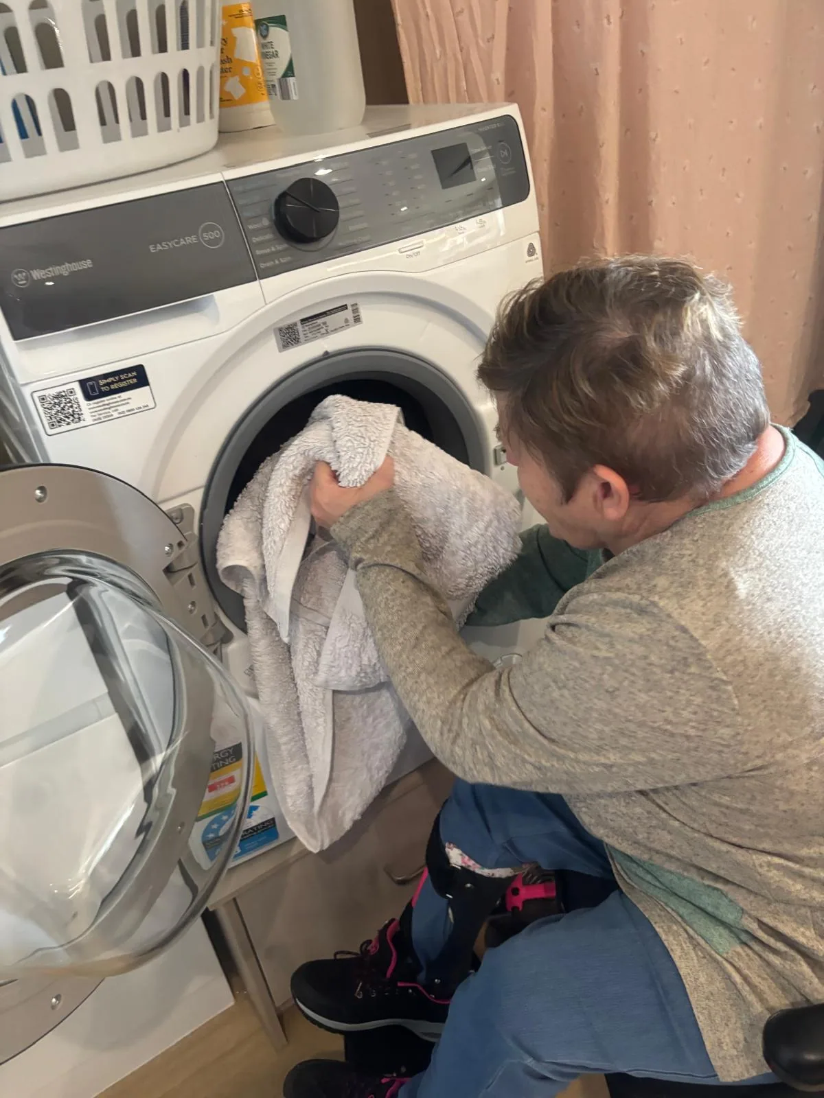 Raelee loading towels into the washing machine in her own home